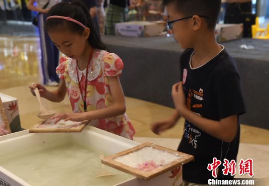 图为小朋友正在制作花草纸。　周毅 摄