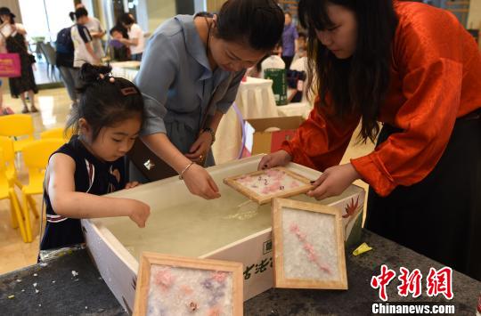 图为小朋友和家长一起学习制作古法花草纸。　周毅 摄