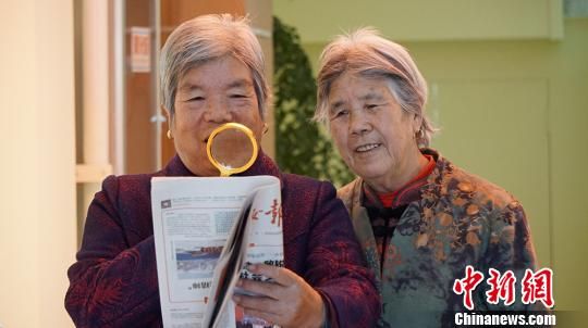 图为社区居民从“便民服务柜”借放大镜看报纸。　魏建军 摄